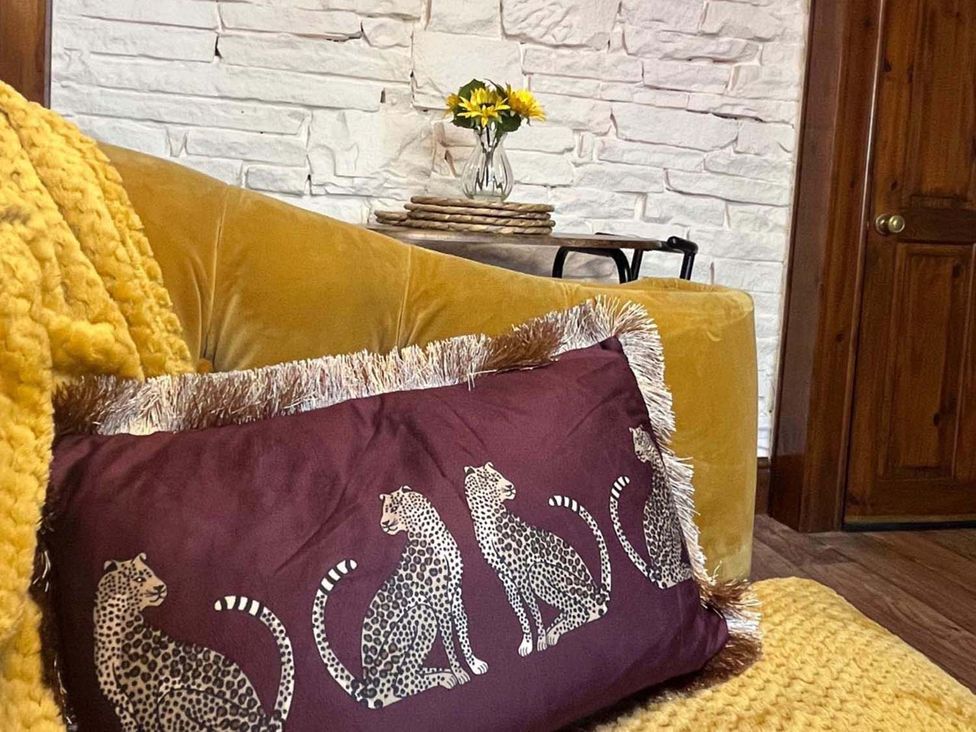A living room with a yellow sofa and decorative pillows at Cozy Cottage Retreat near Haworth log burner in Keighley