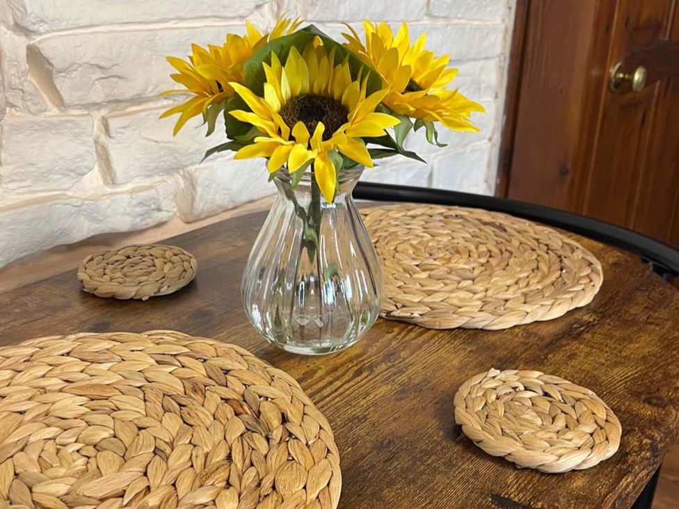 A table with flowers in a vase and coasters at Cozy Cottage Retreat near Haworth log burner, Keighley