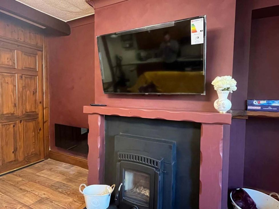 A living room with a television above a fireplace at Cozy Cottage Retreat near Haworth log burner in Keighley