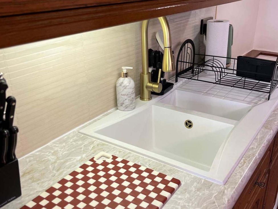 A kitchen with a sink, faucet, and dish rack at Cozy Cottage Retreat near Haworth log burner Keighley