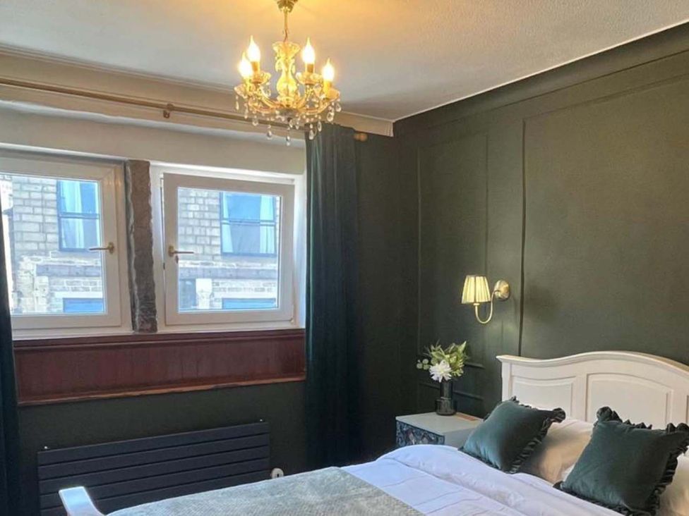 A bedroom with a bed, windows, and a chandelier at Cozy Cottage Retreat near Haworth log burner in Keighley