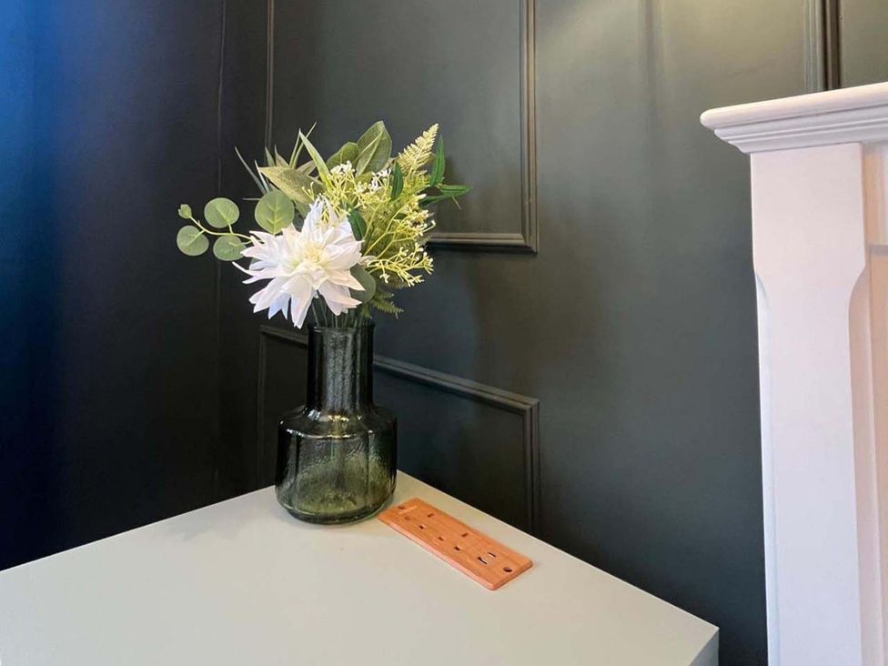 A vase with flowers on a table at Cozy Cottage Retreat near Haworth log burner in Keighley