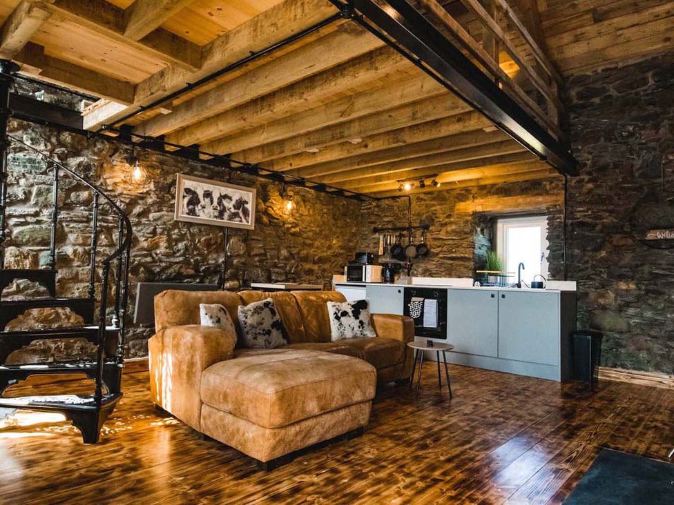 A living room with a sofa and kitchen area at The Milking Shed at Pencraig Pet Friendly near Holyhead