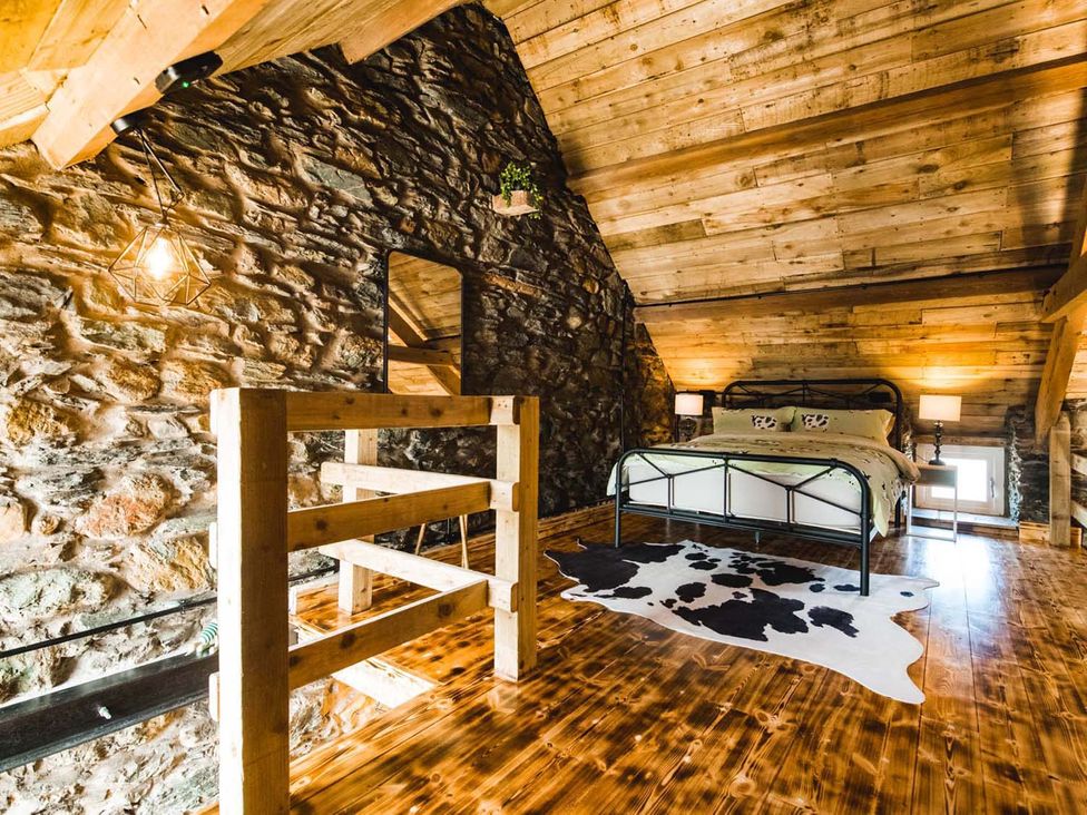 A bedroom with a bed and wooden railing at The Milking Shed at Pencraig Pet Friendly Llanynghenedl near Holyhead