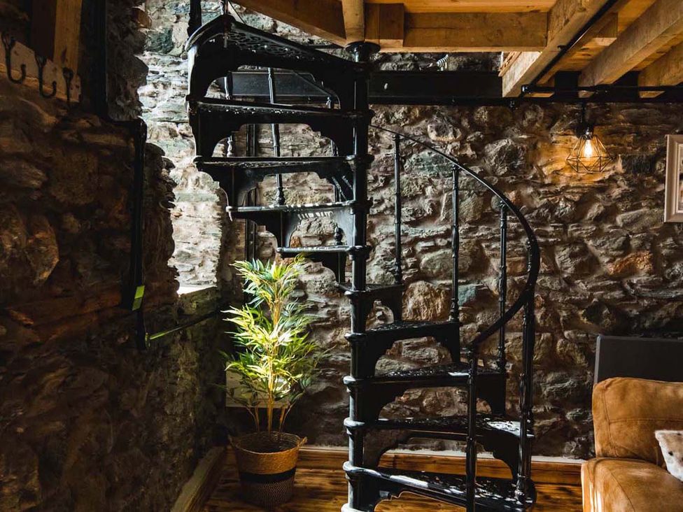 A staircase with a spiral design in a stone wall area at The Milking Shed at Pencraig Pet Friendly near Holyhead