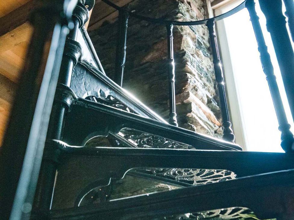 A spiral staircase next to a stone wall at The Milking Shed at Pencraig Pet Friendly Llanynghenedl near Holyhead