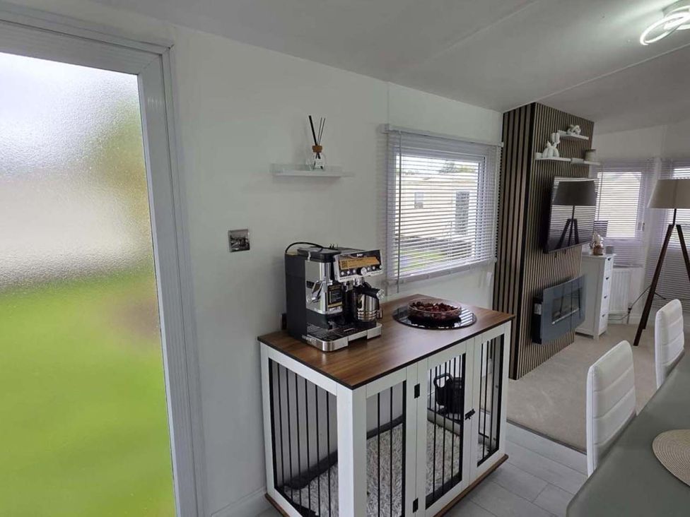 A kitchen area with a coffee machine and dining table at Luxury Cosy Caravan in Cresswell Northumberland