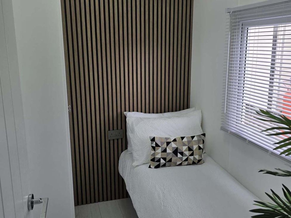 A bedroom with a bed against a wooden wall at Luxury Cosy Caravan in Cresswell Northumberland