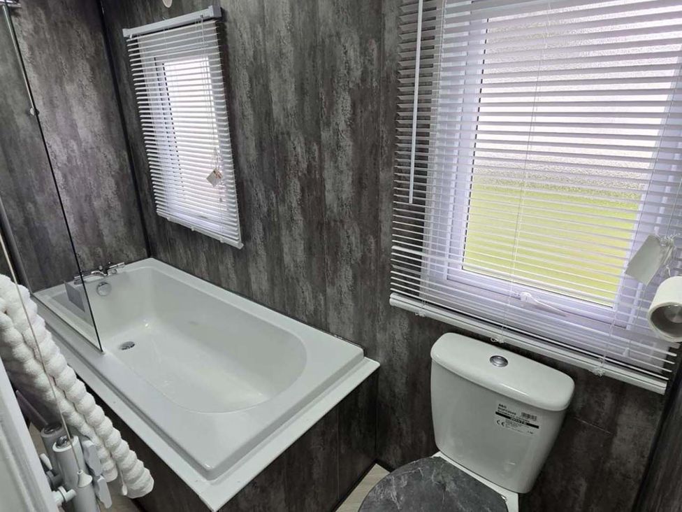 A bathroom with a bathtub and a toilet at Luxury Cosy Caravan in Cresswell Northumberland