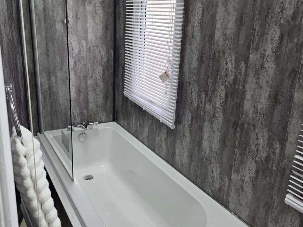 A bathroom with a bathtub and shower screen at Luxury Cosy Caravan in Cresswell Northumberland