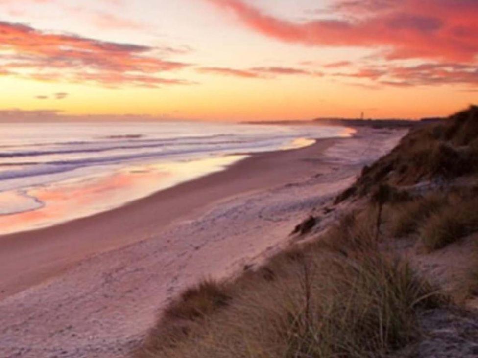 A beach with waves and sand during sunset at Luxury Cosy Caravan in Cresswell Northumberland, Creswell