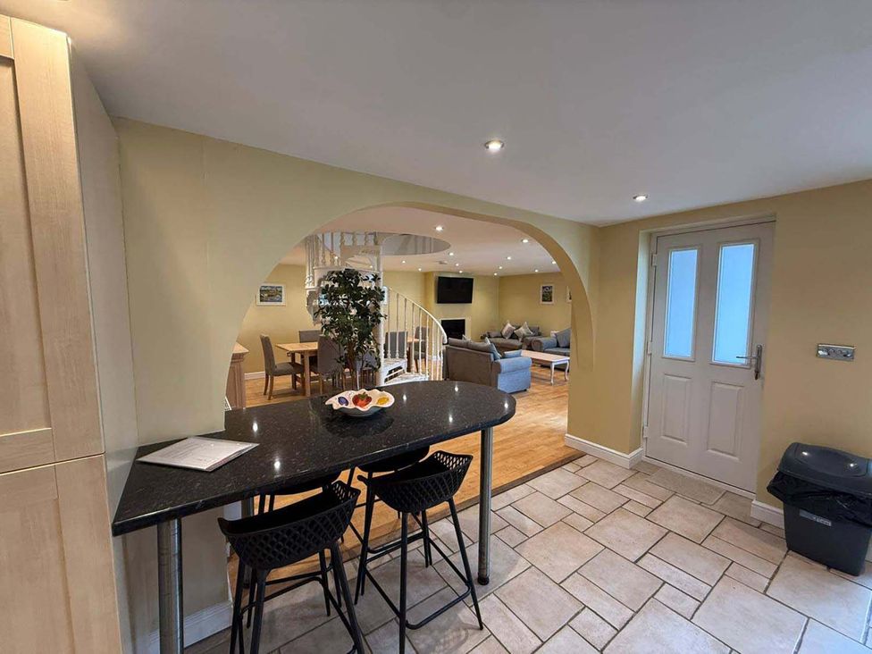A kitchen with bar counter and stools leading to dining area at The Old Barn in Manchester