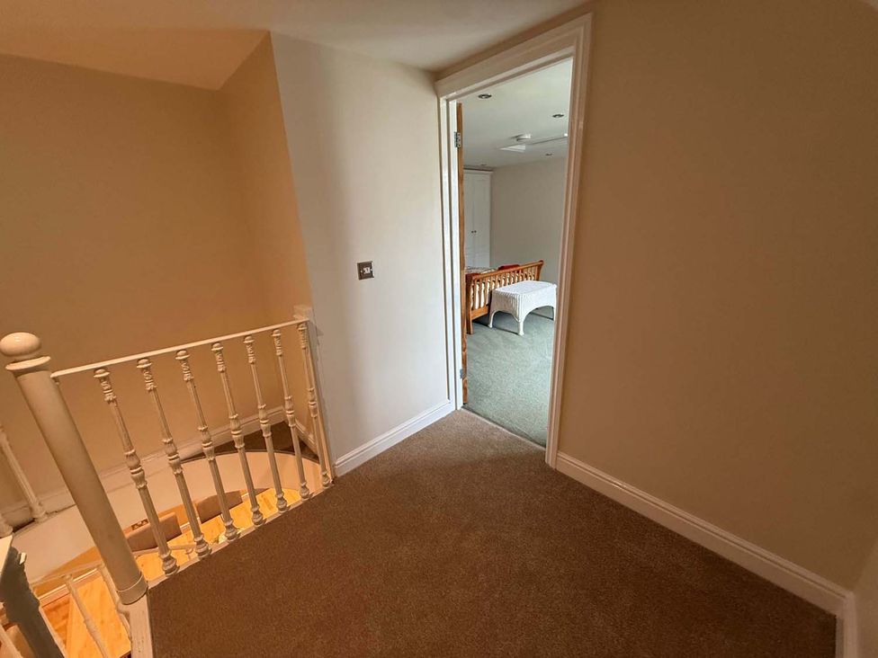 A hallway with a staircase and an open door leading to another room at the property