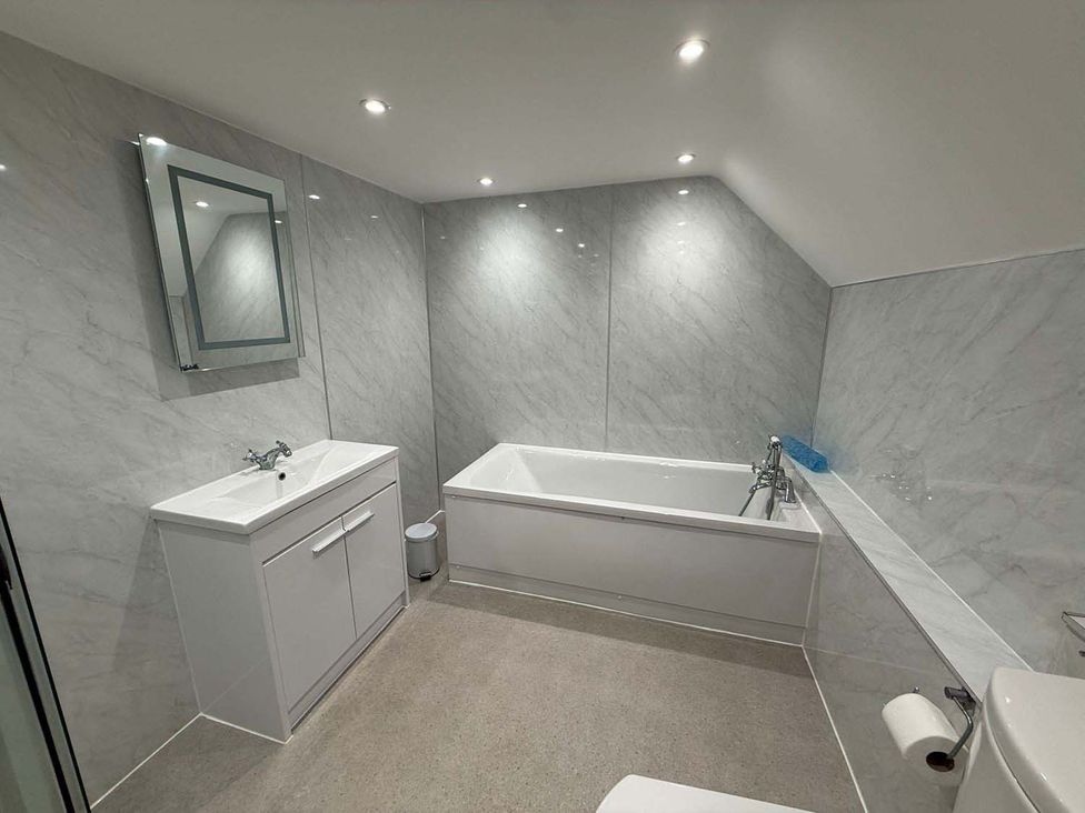 A bathroom with a bathtub, sink, mirror, and toilet