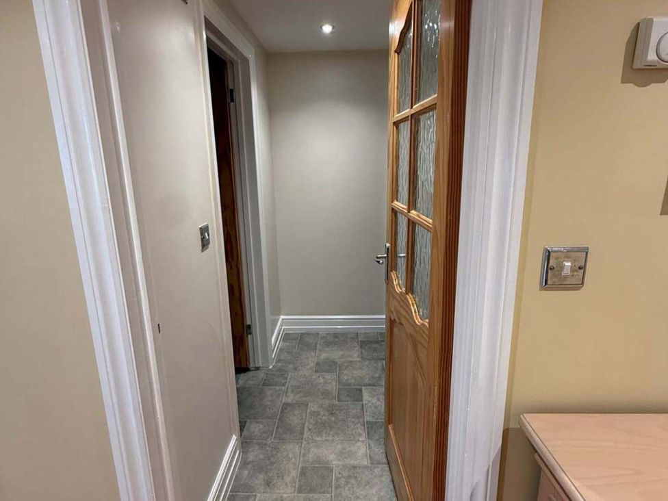 A hallway with a wooden door and light switch at the property in an unspecified location