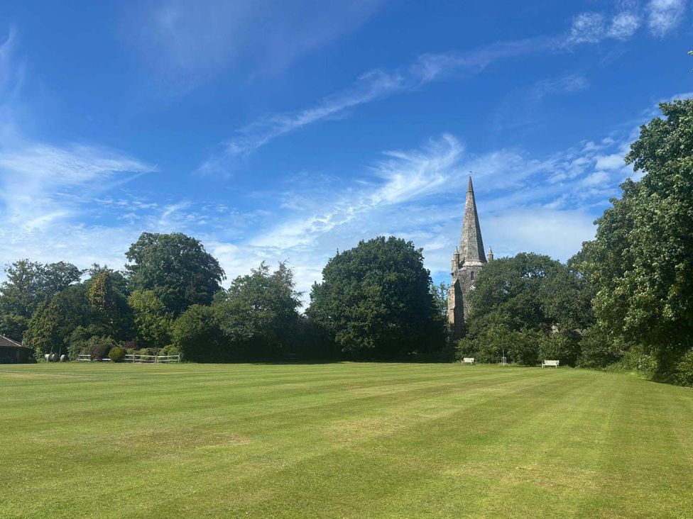 A park area with trees and a church spire in the background