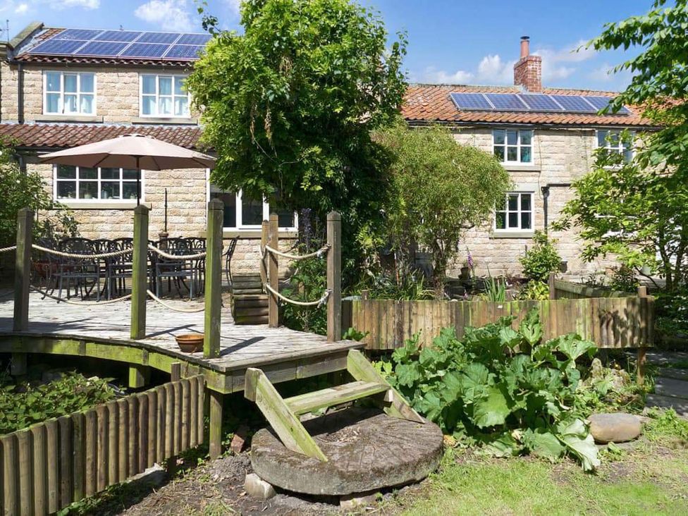 A house with a deck and table set in a garden at The Old Barn in Manchester
