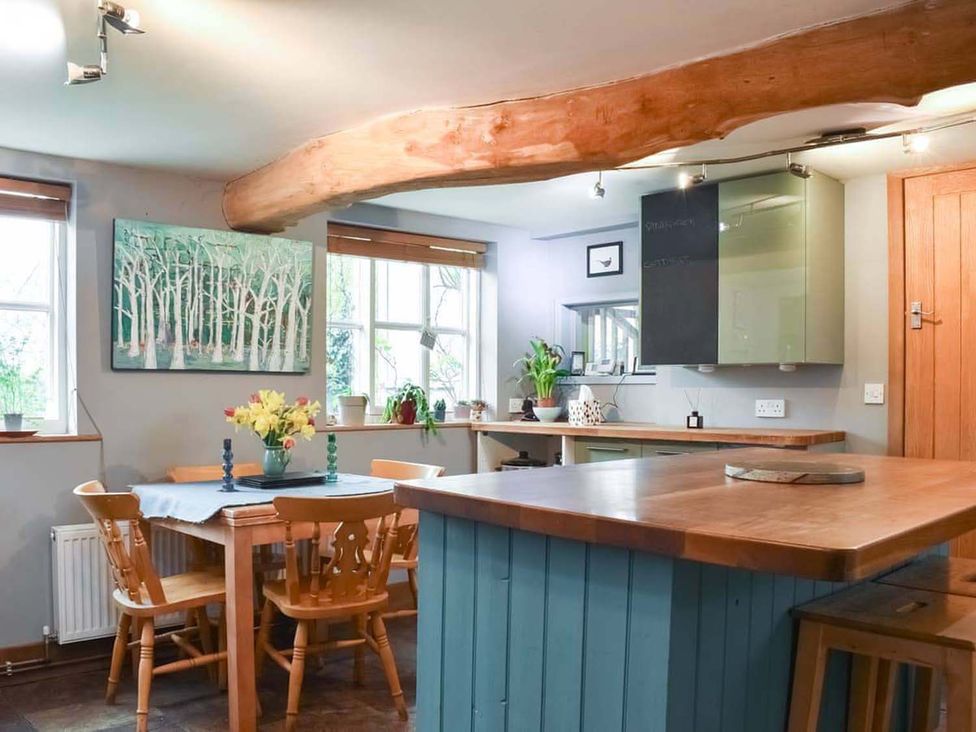 A kitchen with a table and chairs and a cabinet at The Old Barn in Manchester