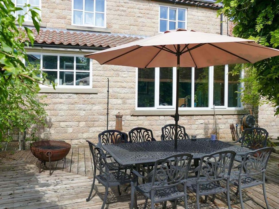 An outdoor dining area with a table and chairs under an umbrella at a residence