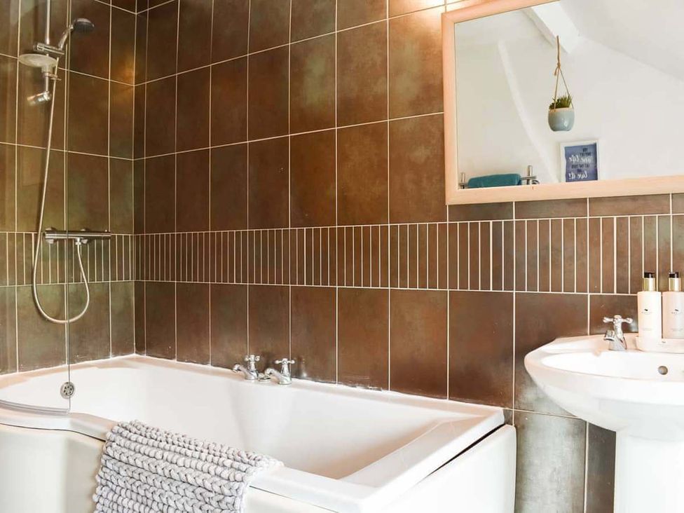 A bathroom with a bathtub, sink, and mirror at the property