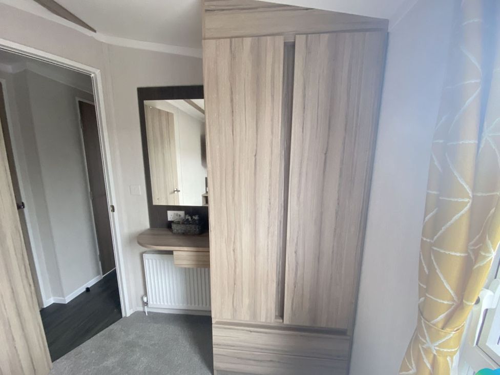 A bedroom with a wardrobe and mirror at The Old Barn in Builth Wells