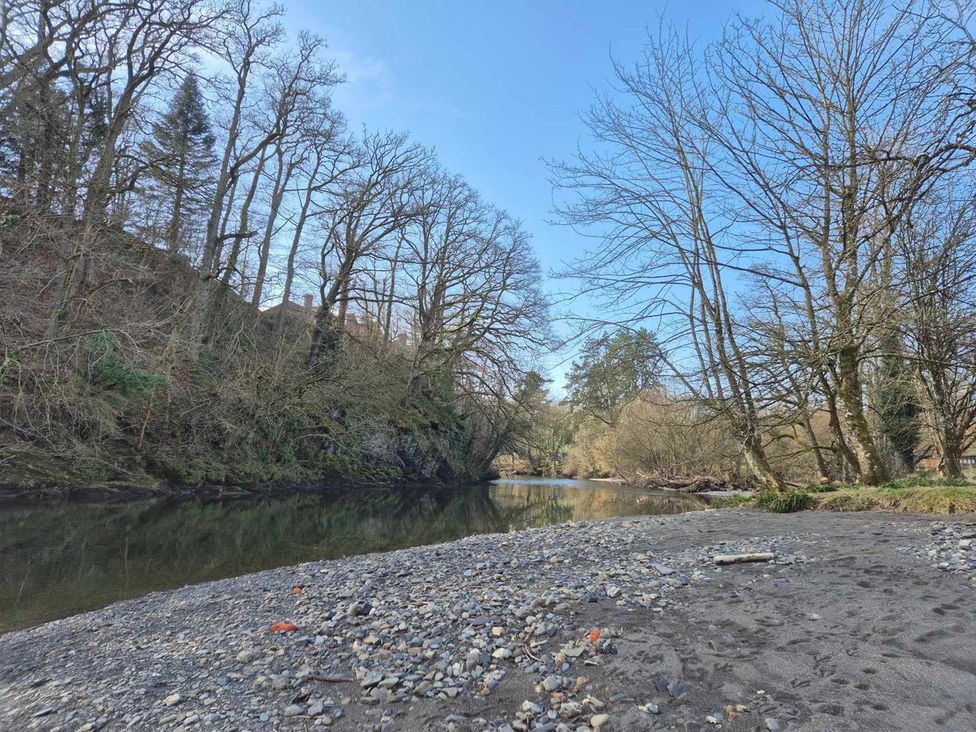 A river surrounded by trees with rocky sand at a scenic location in Builth Wells