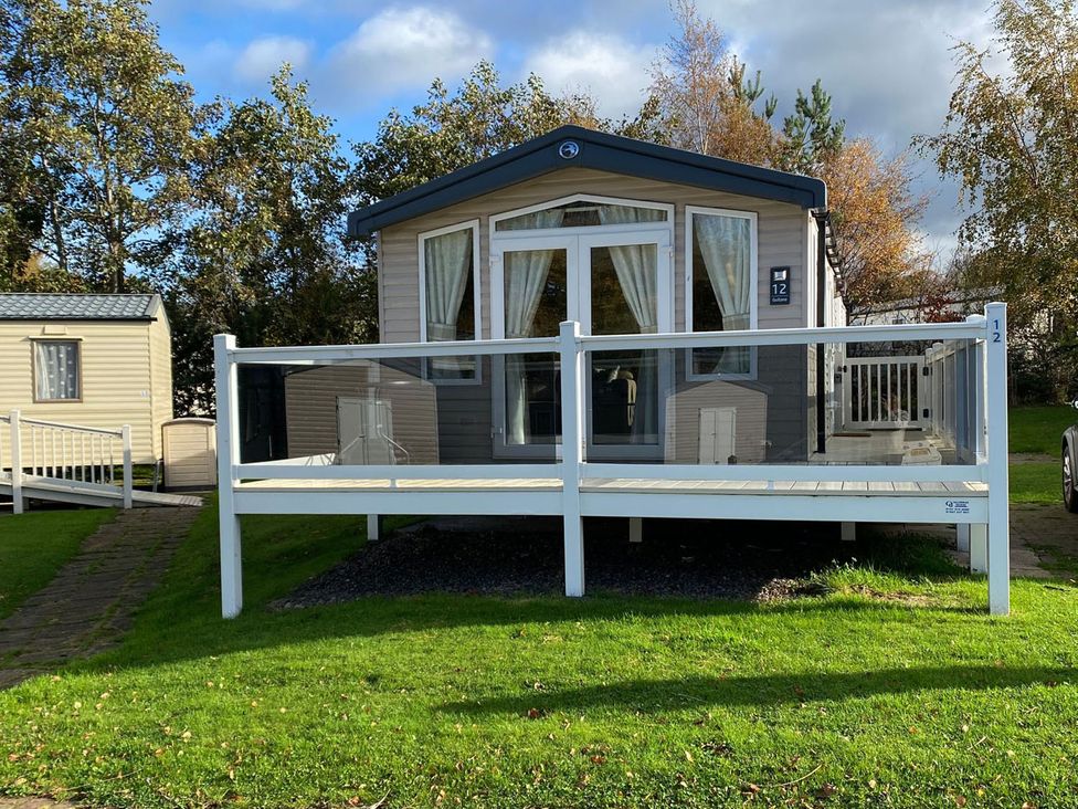 A mobile home with a deck and steps at a holiday park location