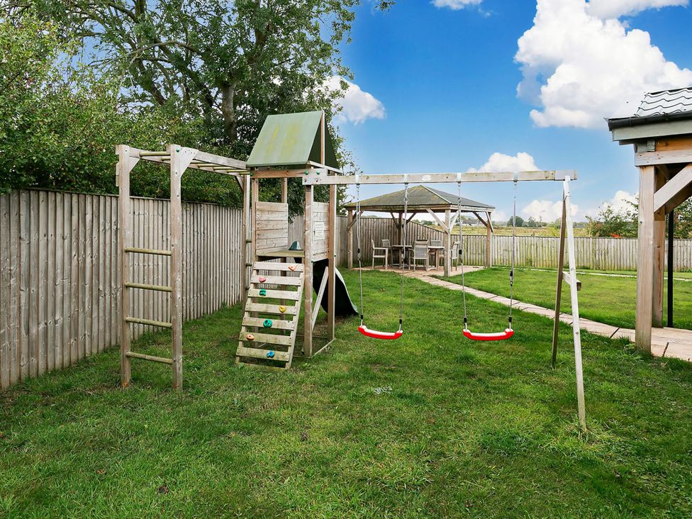 A play structure with swings and a bench in a garden