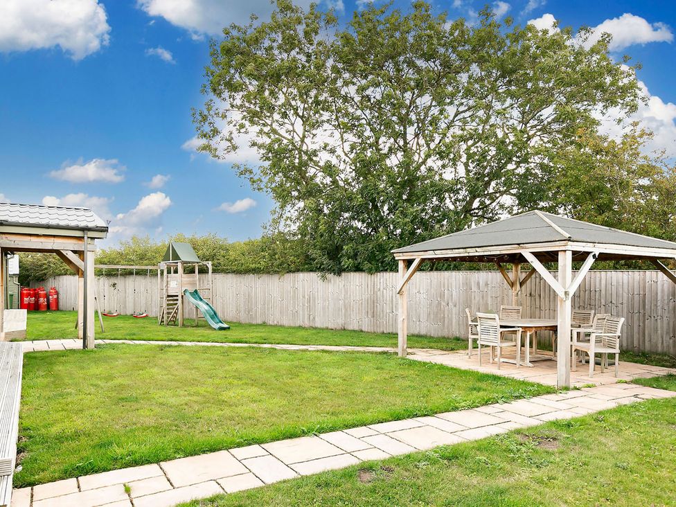A garden with a playground, seating area and green grass at a property