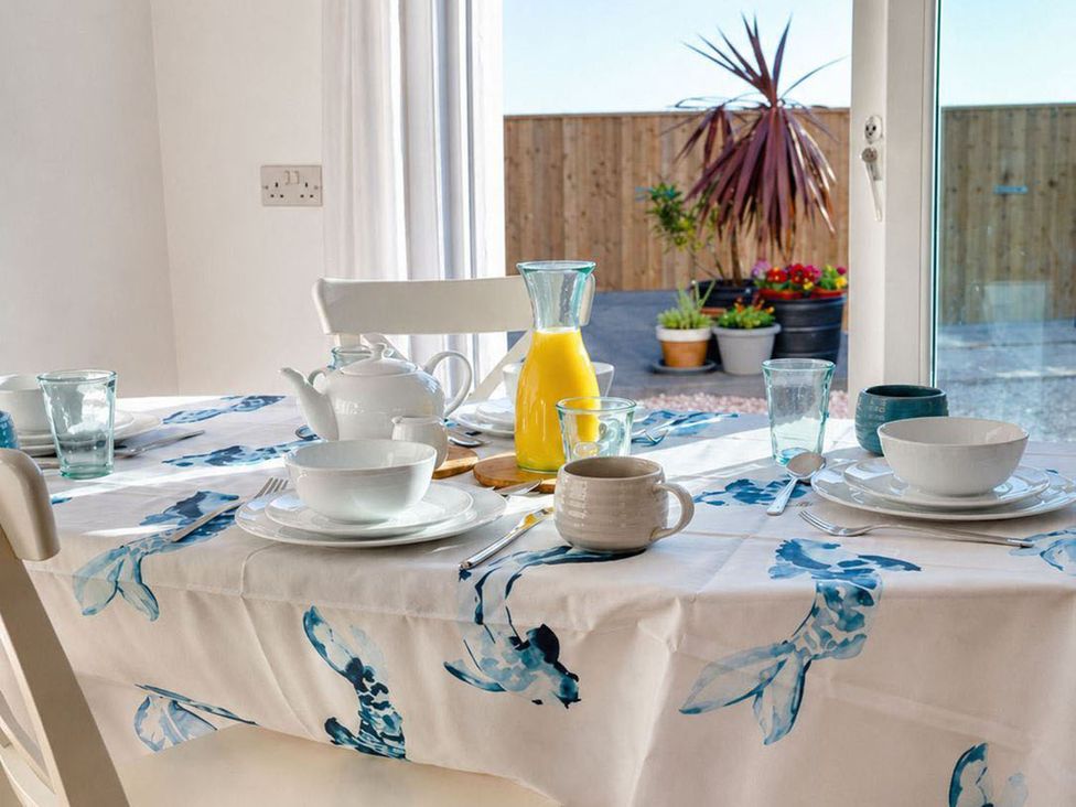 A dining table set with mugs, glasses, and plates at the property in 