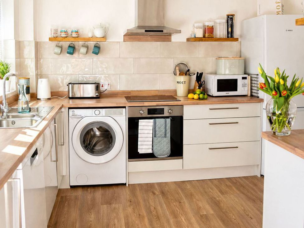 A kitchen with washing machine and appliances at The Old Barn in Manchester
