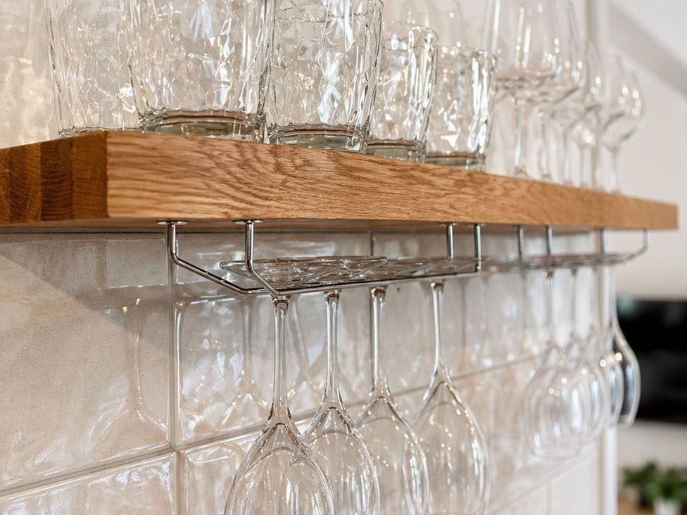 A glass shelf with various glasses in a kitchen