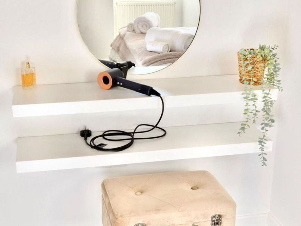 A bathroom with a mirror and hair dryer on a shelf at 