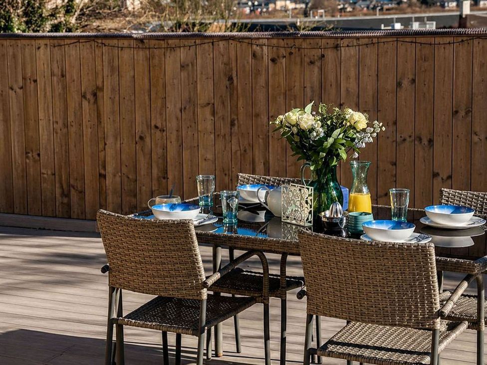 An outdoor dining area with a table set for a meal with flowers and drinks