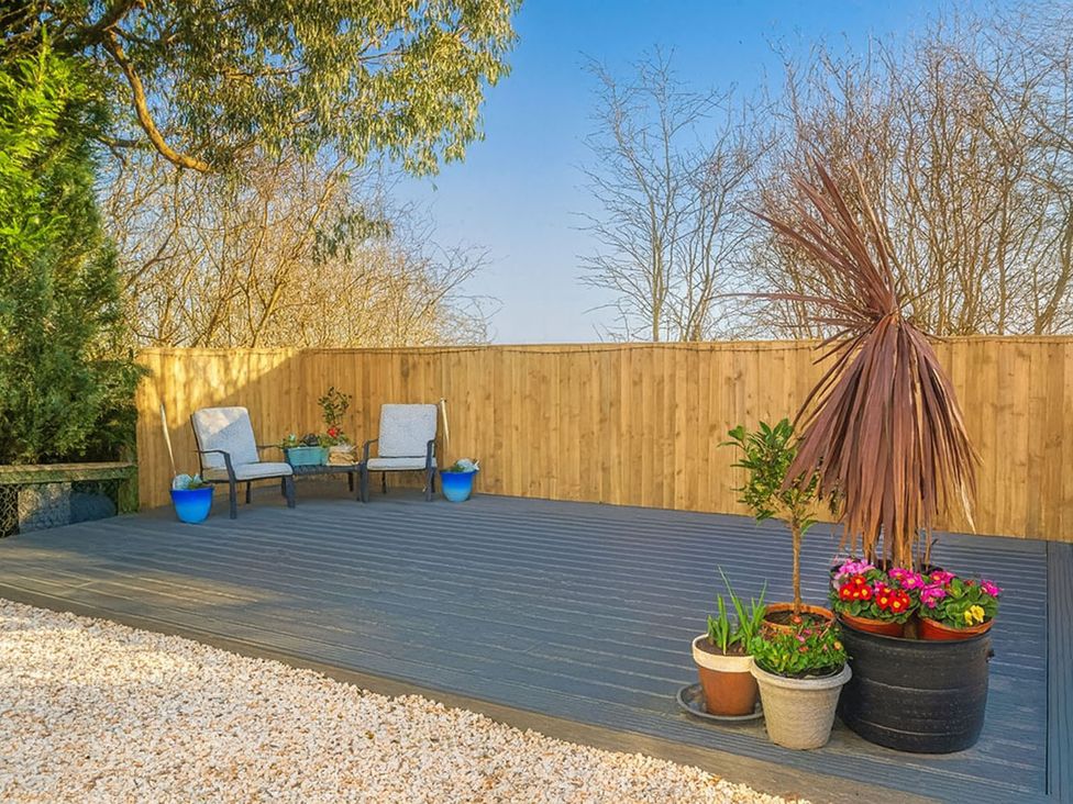 A garden with decking, potted plants and chairs at The Old Barn in Manchester