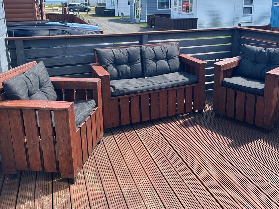 A seating area with outdoor sofa and chairs in an outdoor area