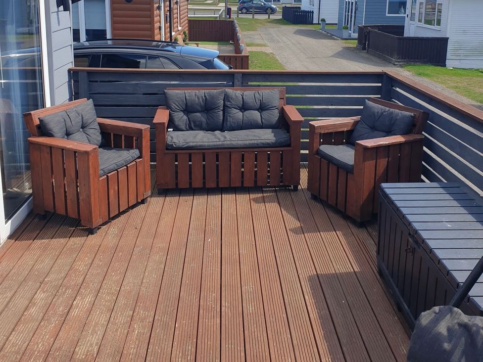 An outdoor seating area with chairs and a sofa on a deck