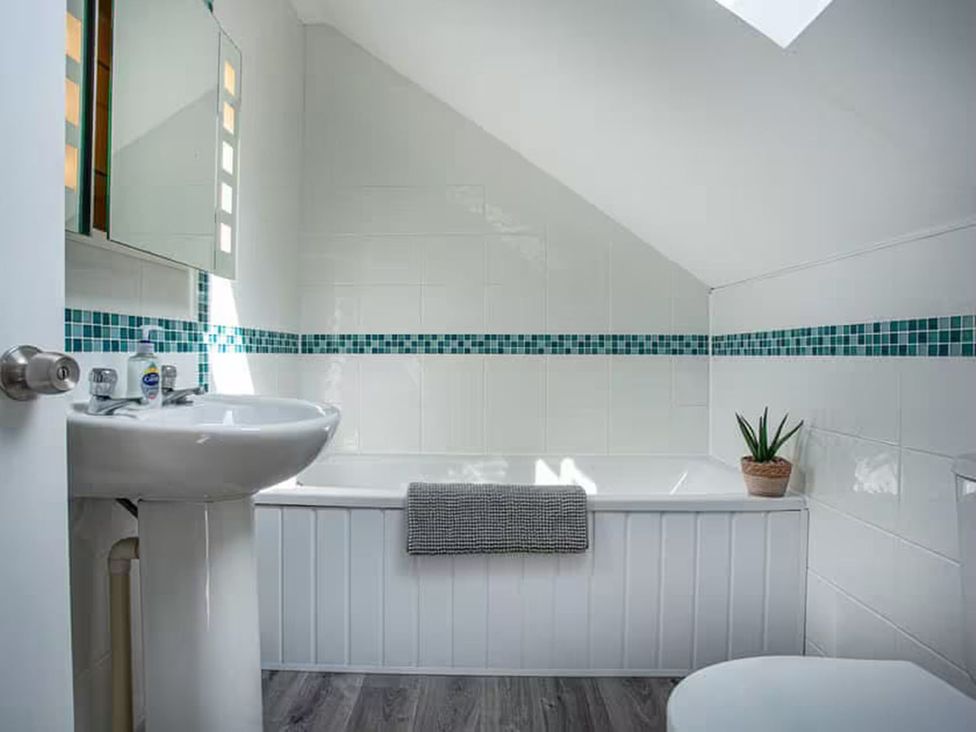 A bathroom with a sink, bathtub and mirror at Spacious 3 Bed House Sleeps 6 Parking Wifi in Newquay