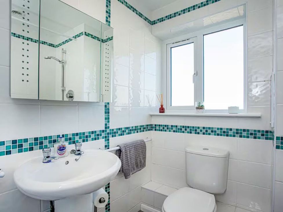 A bathroom with a sink, mirror, shower, and toilet at Spacious 3 Bed House Sleeps 6 Parking Wifi in Newquay