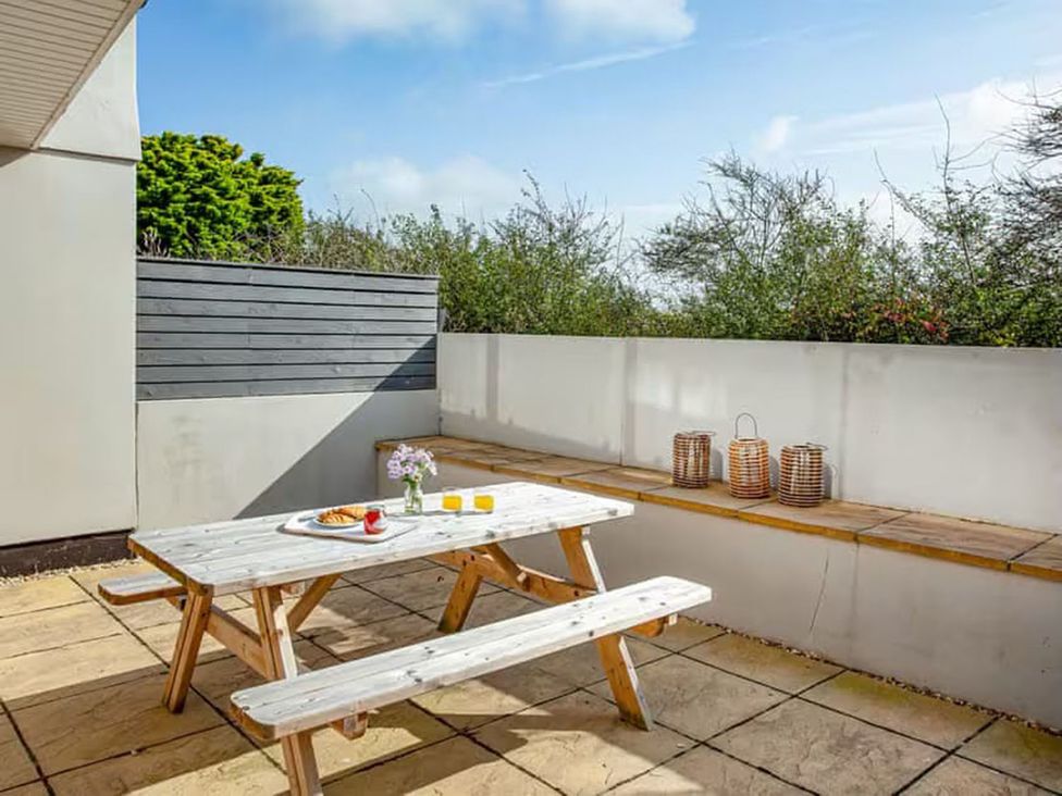 An outdoor patio with a table and bench at Spacious 3 Bed House Sleeps 6 Parking Wifi Newquay