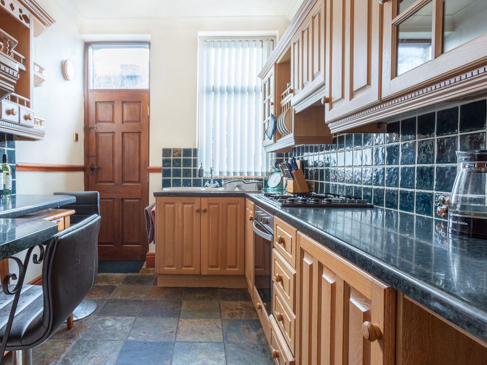 A kitchen with wooden cabinets and tiles at Haworth Village House Sleeps 6 Parking Pets, Cross Roads