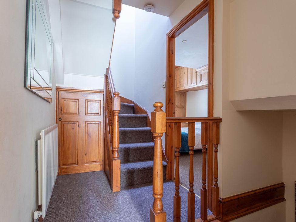 A staircase with wooden railing and door at Haworth Village House Sleeps 6 Parking Pets, Cross Roads