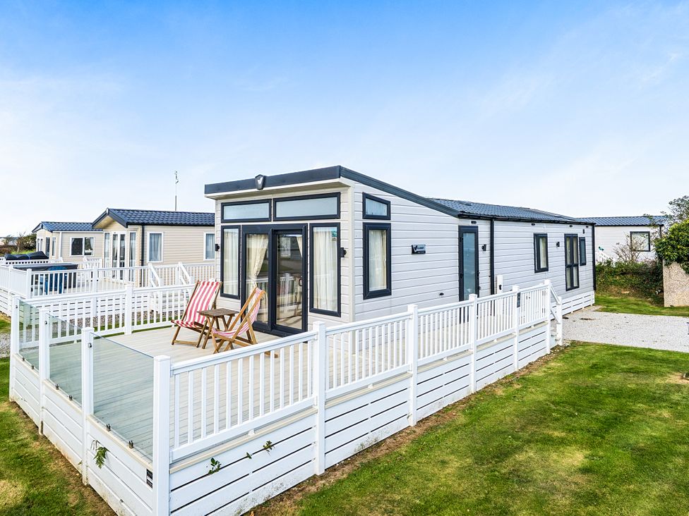 A caravan with a deck and chairs at 2Br Lodge Pool Fireplace PetsOK Parking Goonhavern