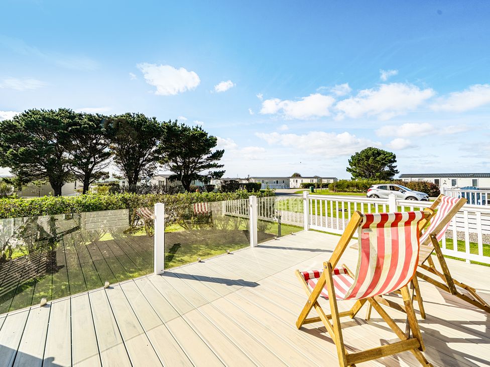 A view of deck chairs on a wooden deck with trees and a blue sky at 2Br Lodge Pool Fireplace PetsOK Parking in Goonhavern