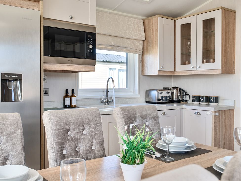 A kitchen with a refrigerator, microwave, and dining table at 2Br Lodge Pool Fireplace PetsOK Parking in Goonhavern