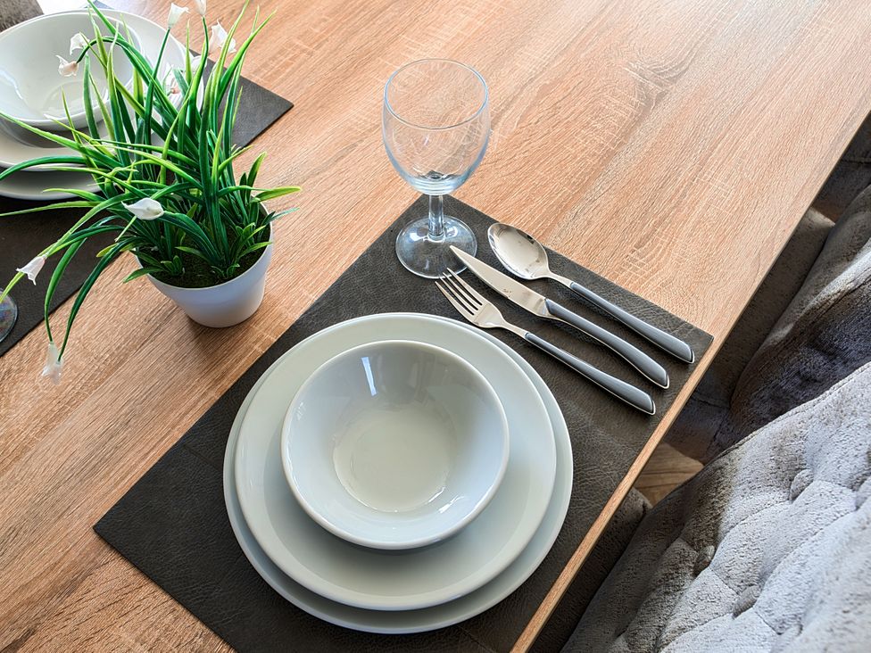 A dining table set with plates, cutlery, and a glass at 2Br Lodge Pool Fireplace PetsOK Parking Goonhavern