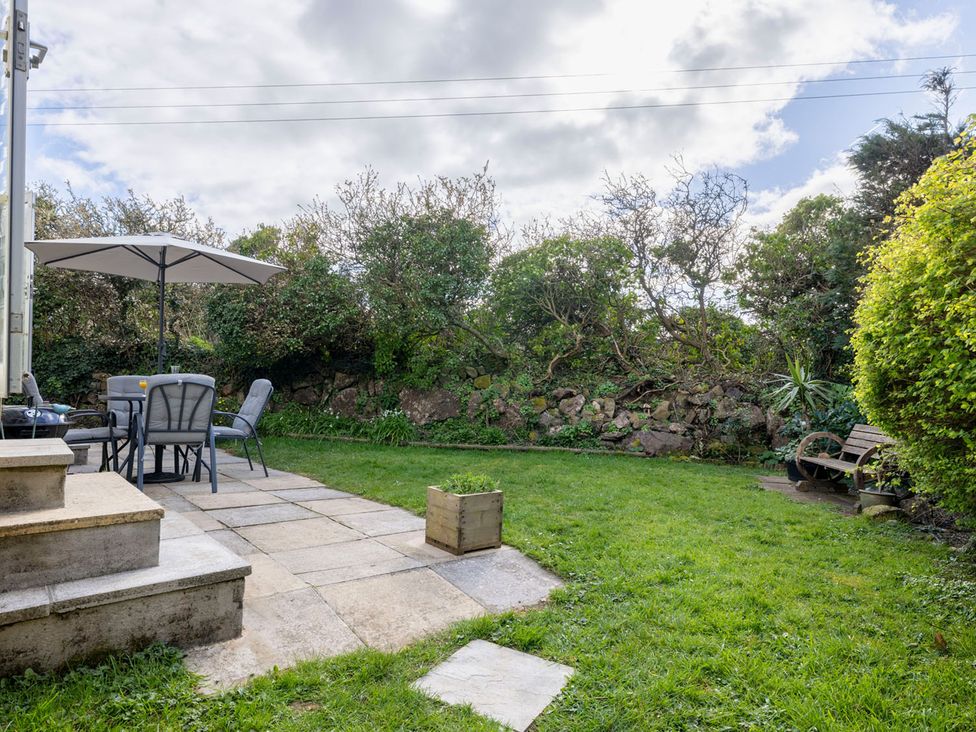 A garden with a table and chairs and an umbrella at Coastal Hideaway in Cornwall Dog Friendly Goldsithney
