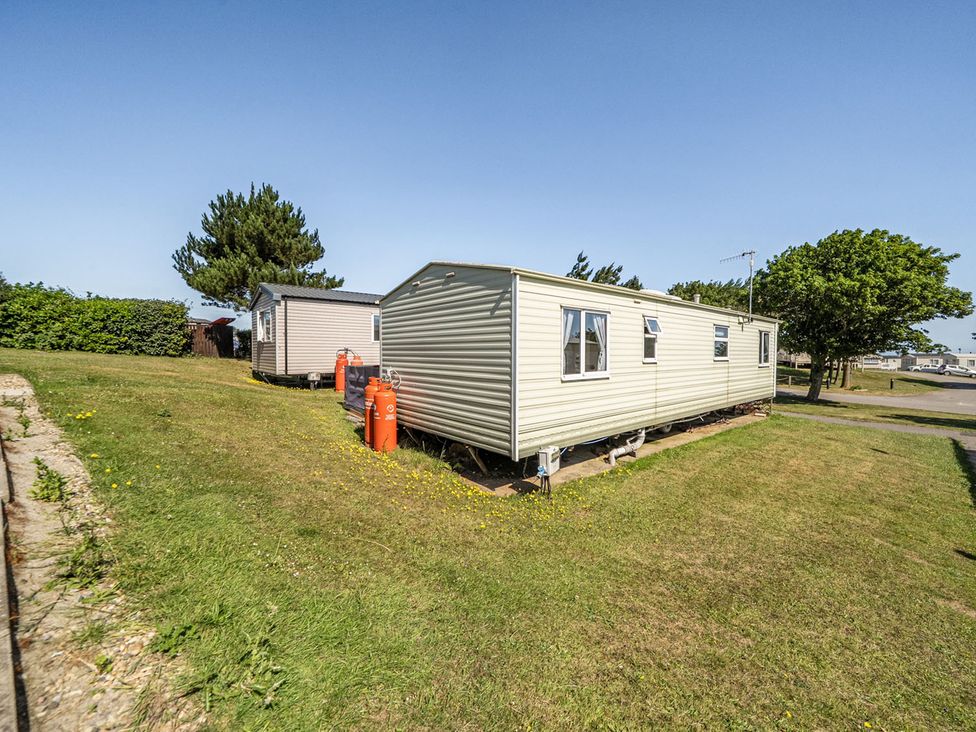 A static caravan with gas cylinders in a grassy area at 3 Bed Sleeps 8 Sea View Pets Parking Reighton Gap near Filey