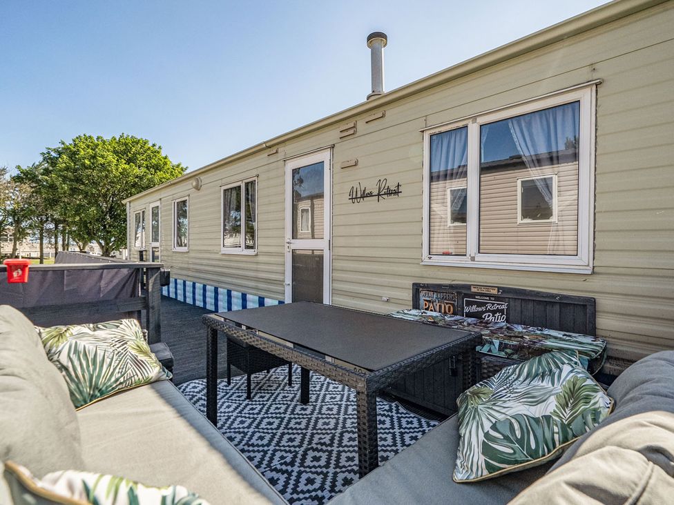 A mobile home with patio furniture at Willows Retreat in Reighton Gap near Filey