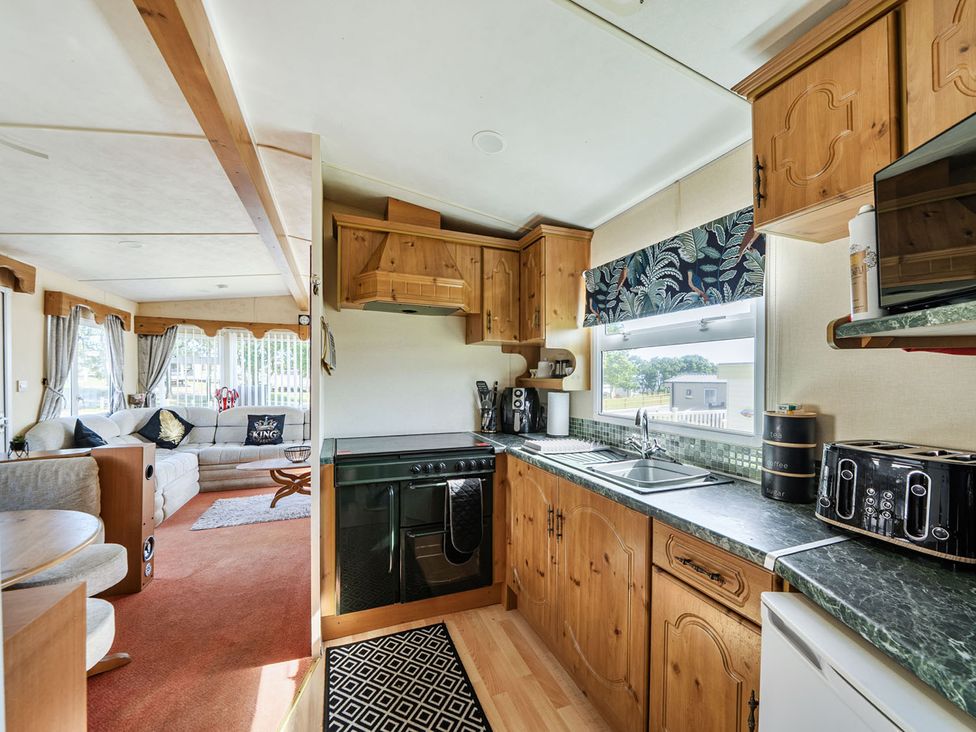 A kitchen and living area with a sofa and dining table at 3 Bed Sleeps 8 Sea View Pets Parking Reighton Gap near Filey